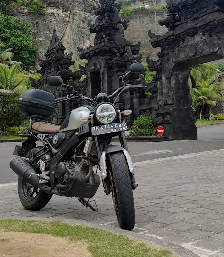 Scrambler with top box at a Balinese temple gate