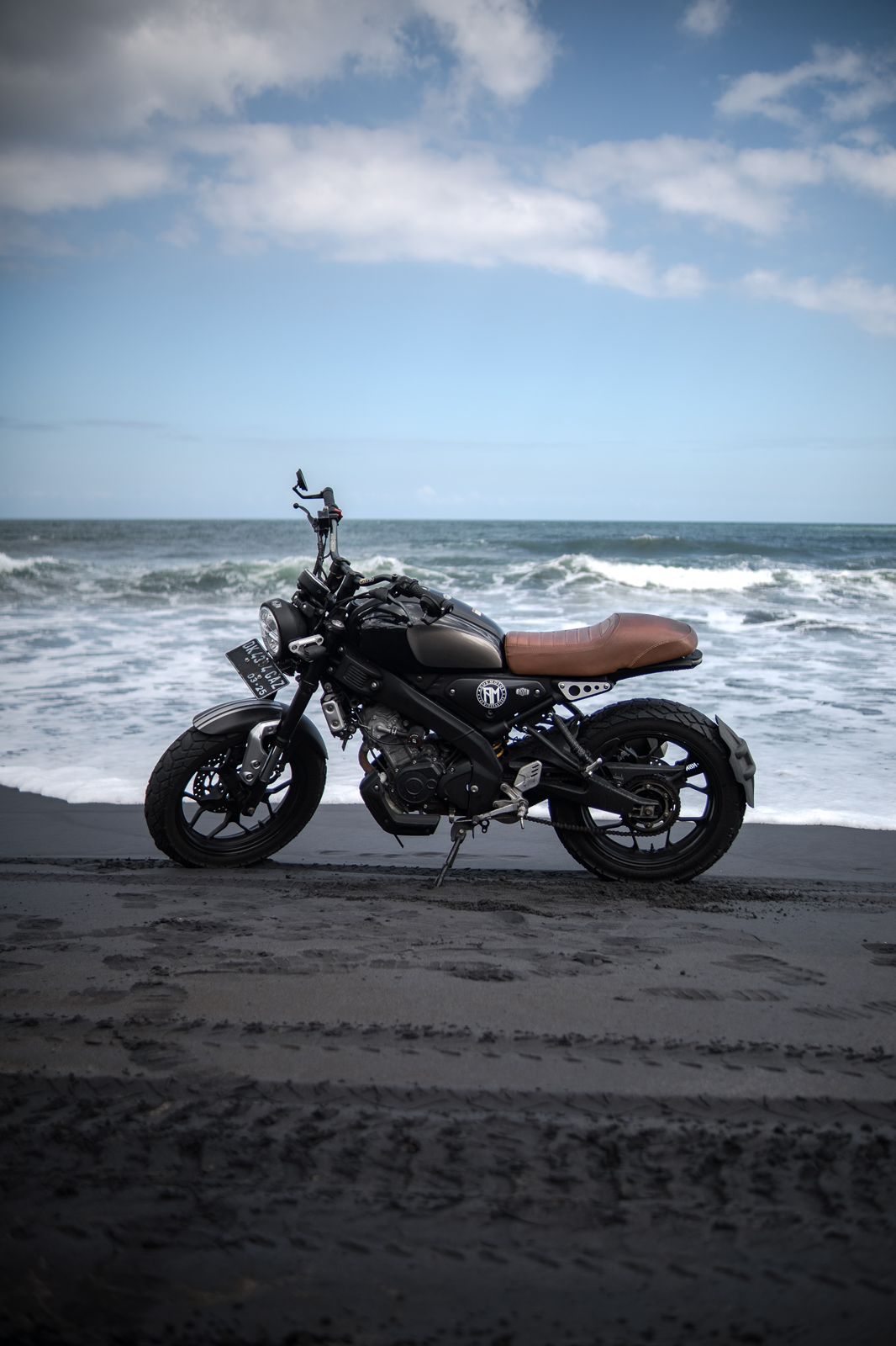 Custom scrambler parked by a Balinese temple at sunset